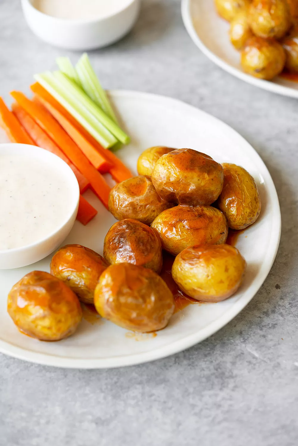 A plate of crispy little potatoes, carrots, and celery with dips.
