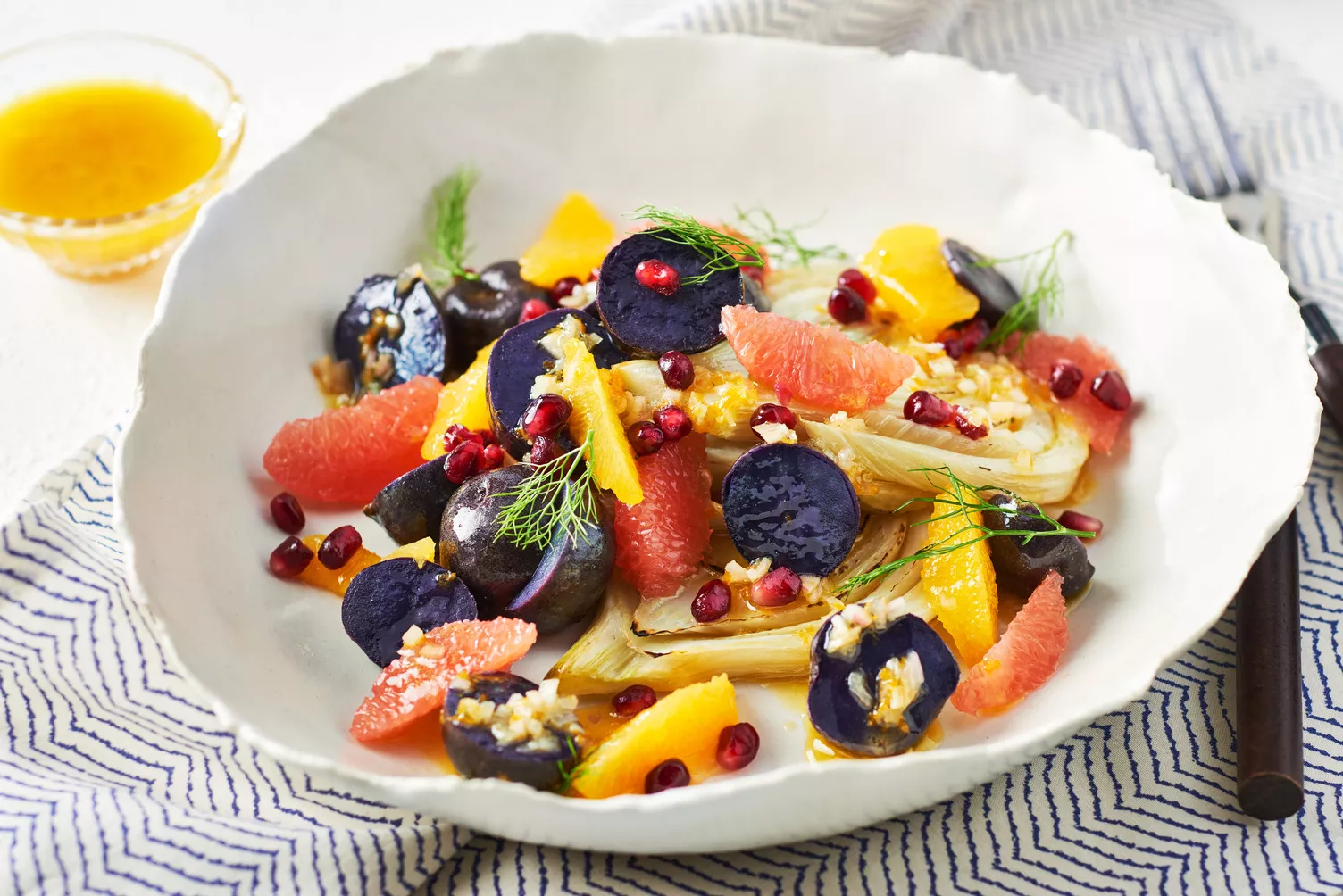 A bowl of little potatoes with fennel and colourful fruits and veggies.