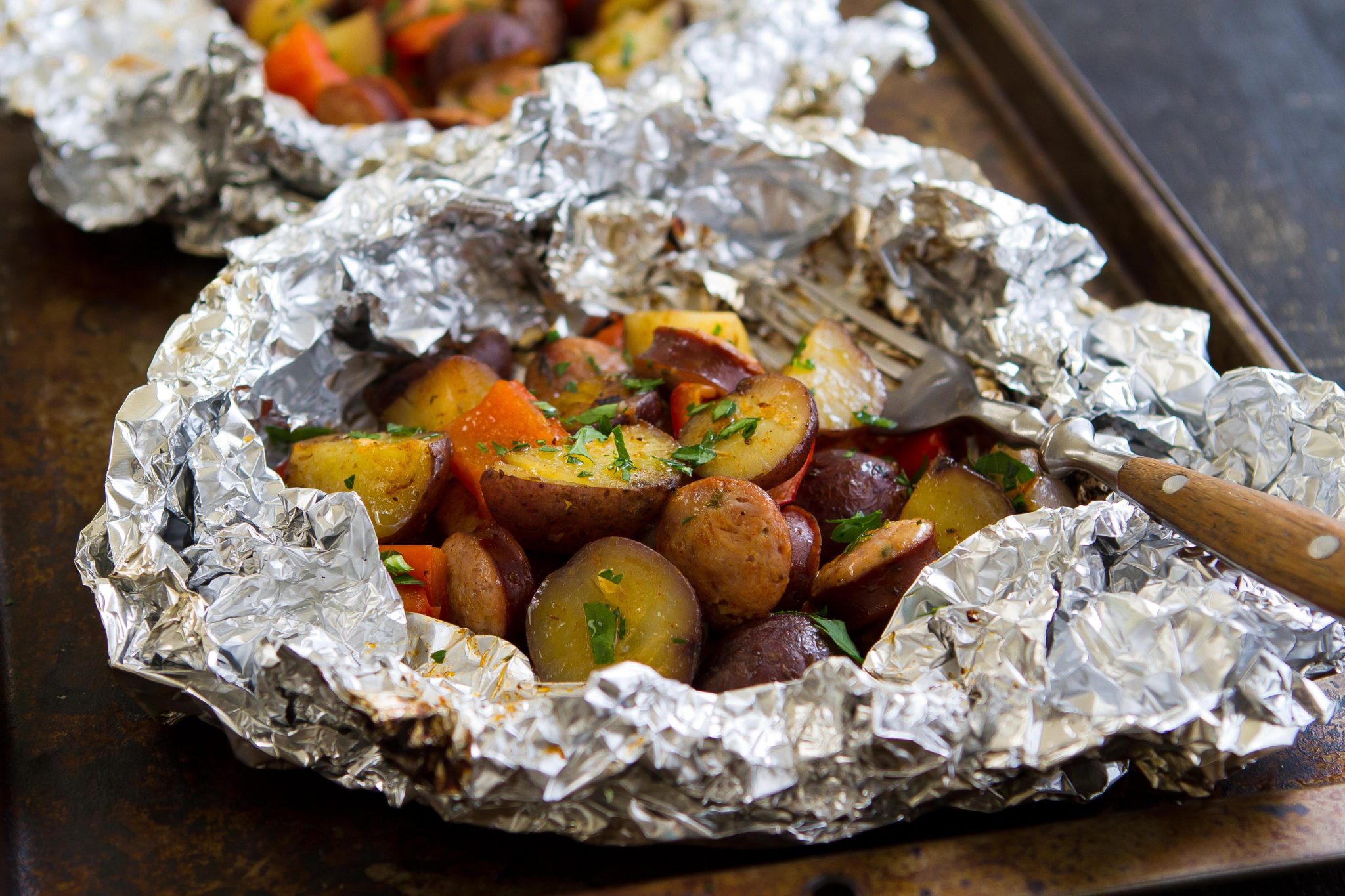 A foil packet with grilled sausage and potatoes.