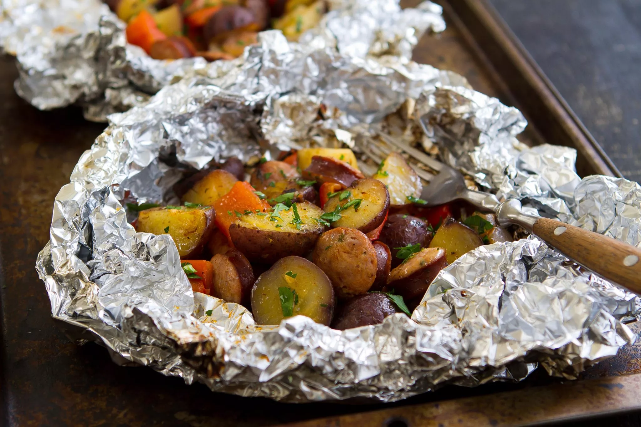 A foil packet with grilled sausage and potatoes.