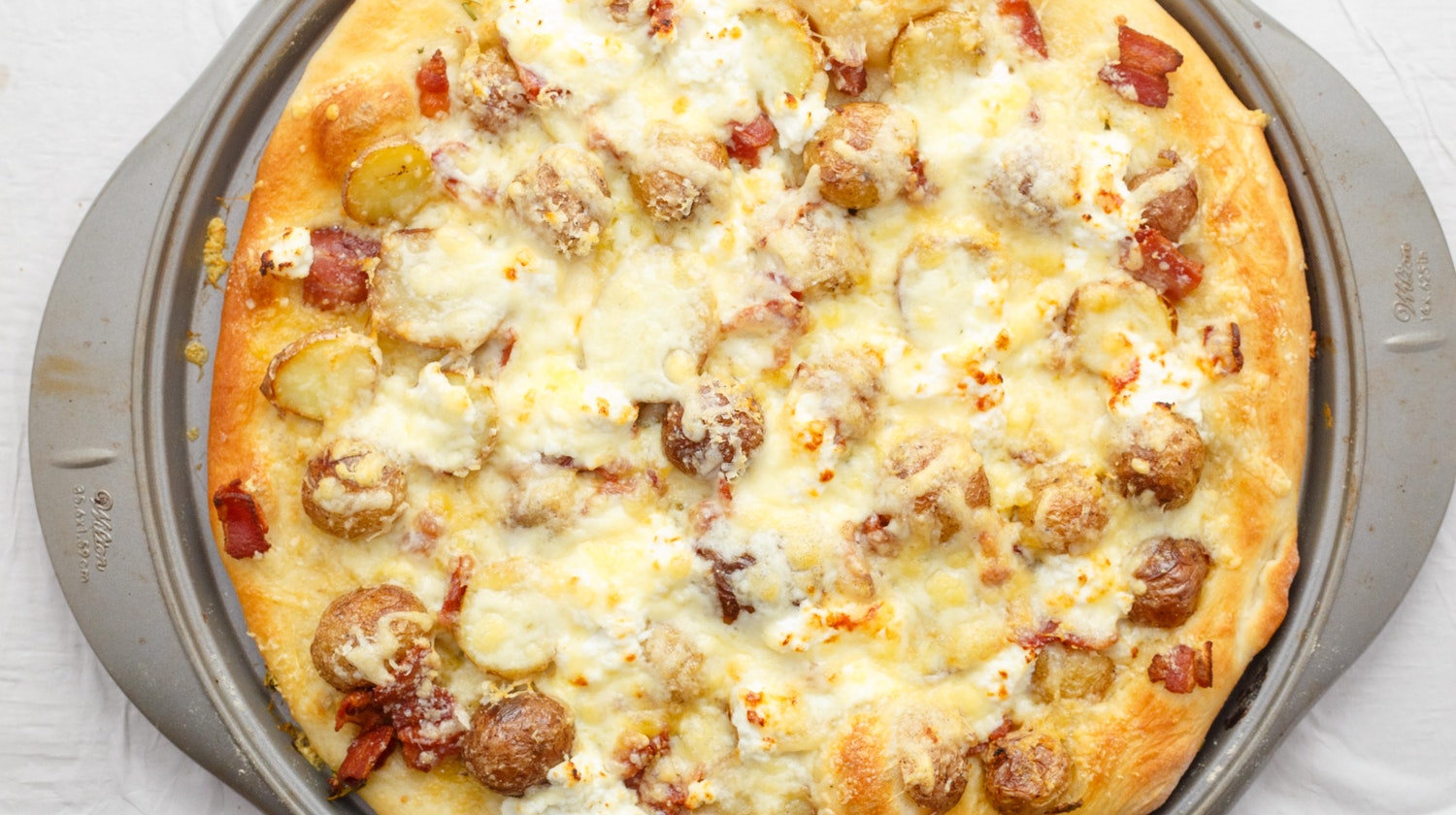 A pizza pan of thin crust bacon potato pizza